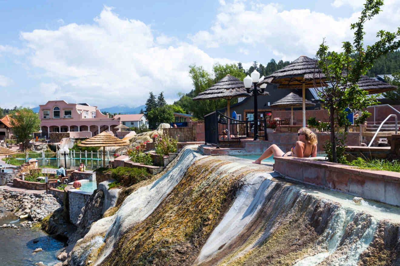 A woman relaxes on a waterfall at a resort.