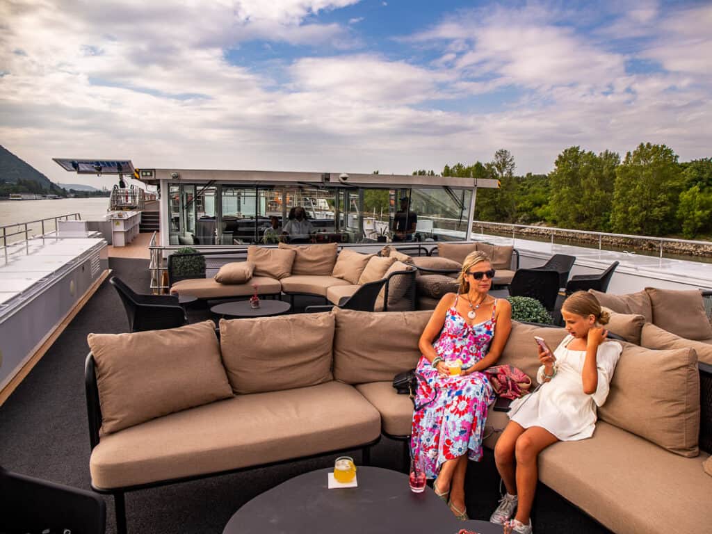 Mom and daughter sitting on a couch with drinks on a cruise ship