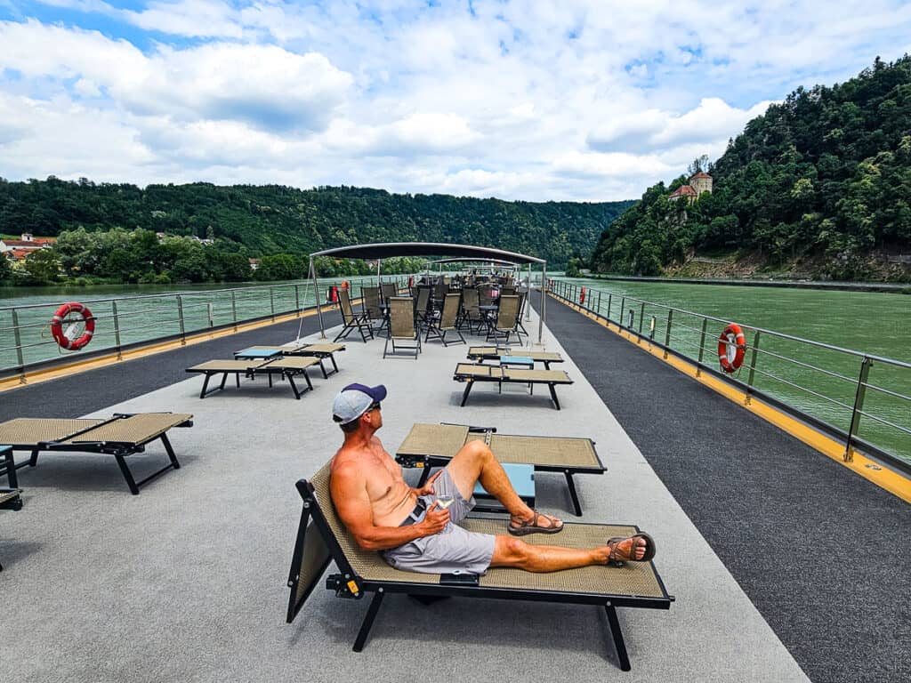 Man sitting on a deck chair on a cruise ship looking at the mountain view