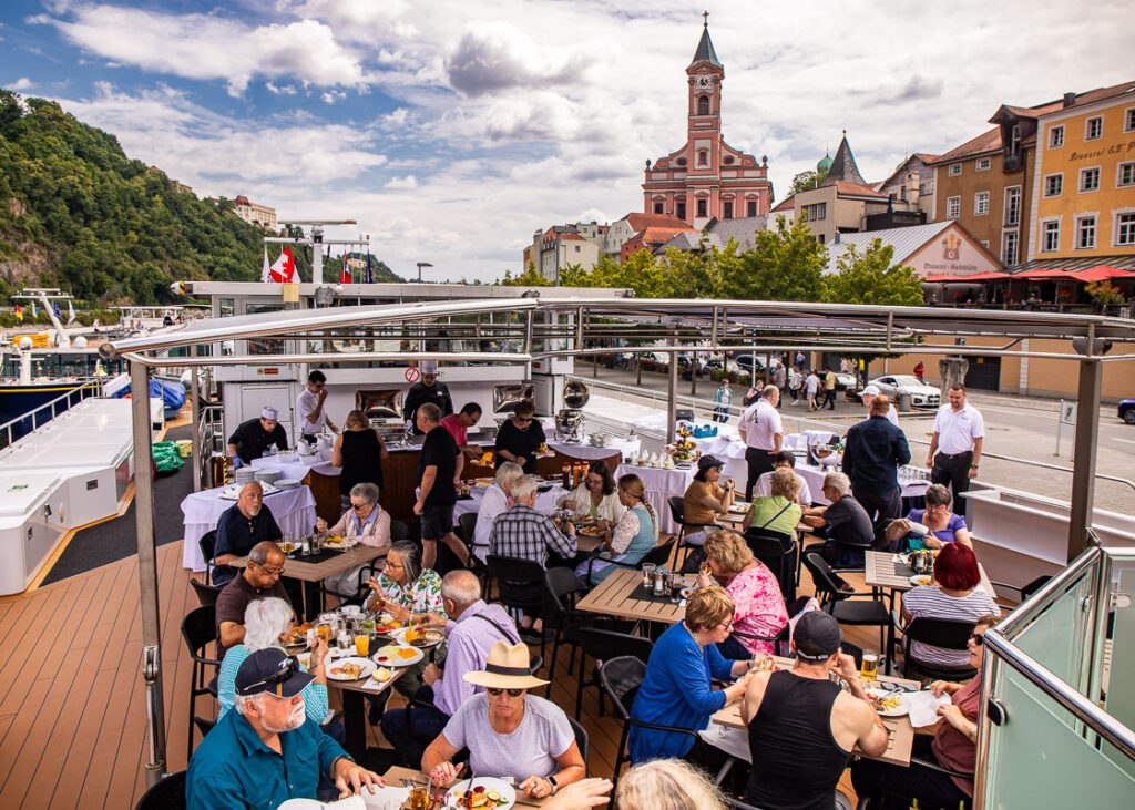 People sitting down having lunch on a cruise ship with city background