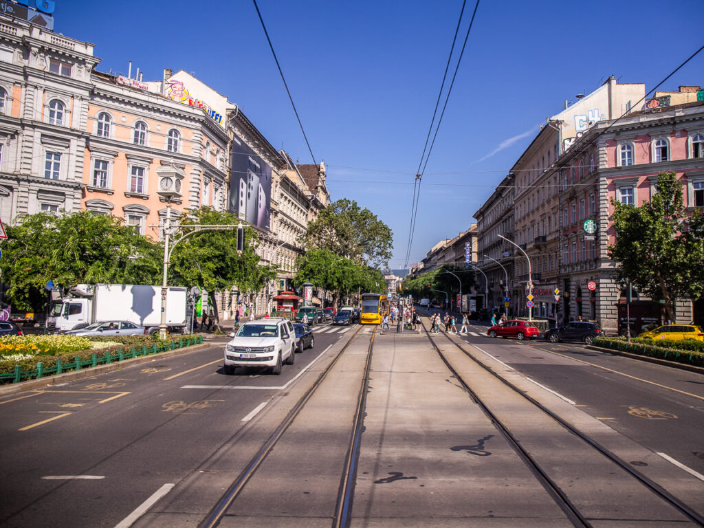 A street running through a city with train tracks and cars