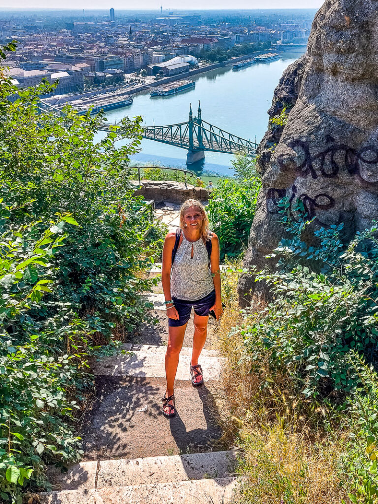 Woman hiking up steps with a bridge and river behind her