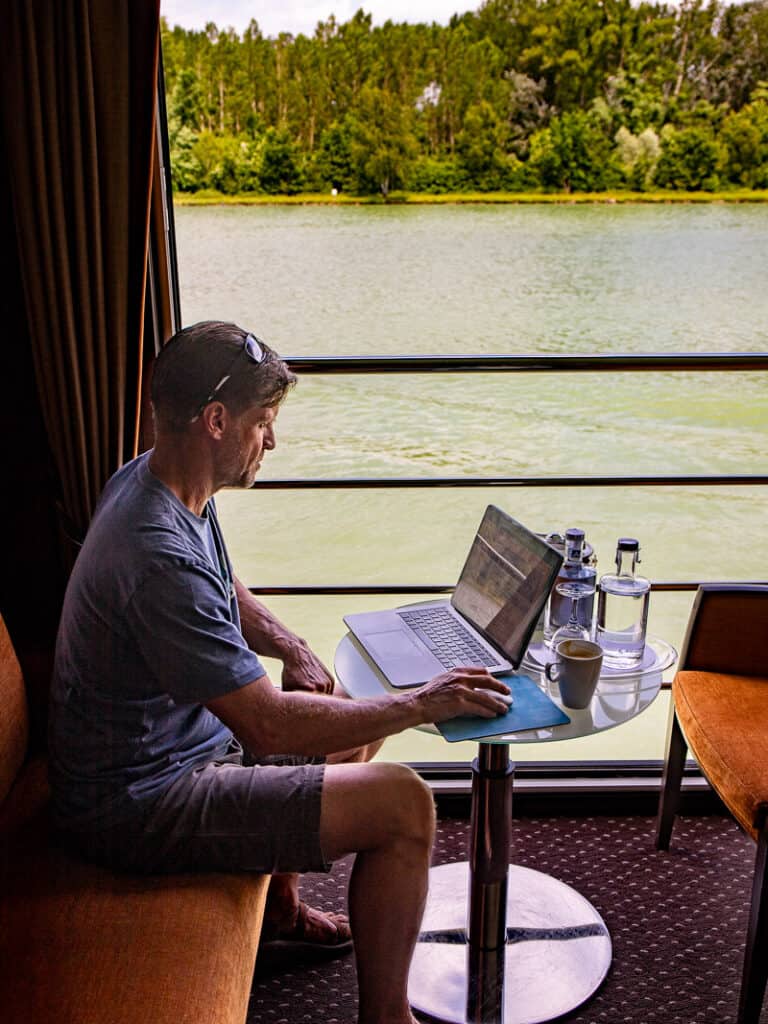 Man working on a computer with a view of the river