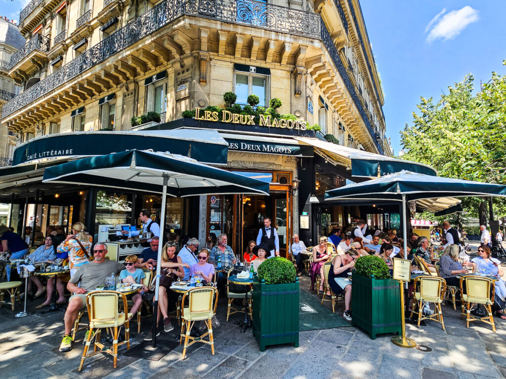 people sitting outside cafe de flore in paris