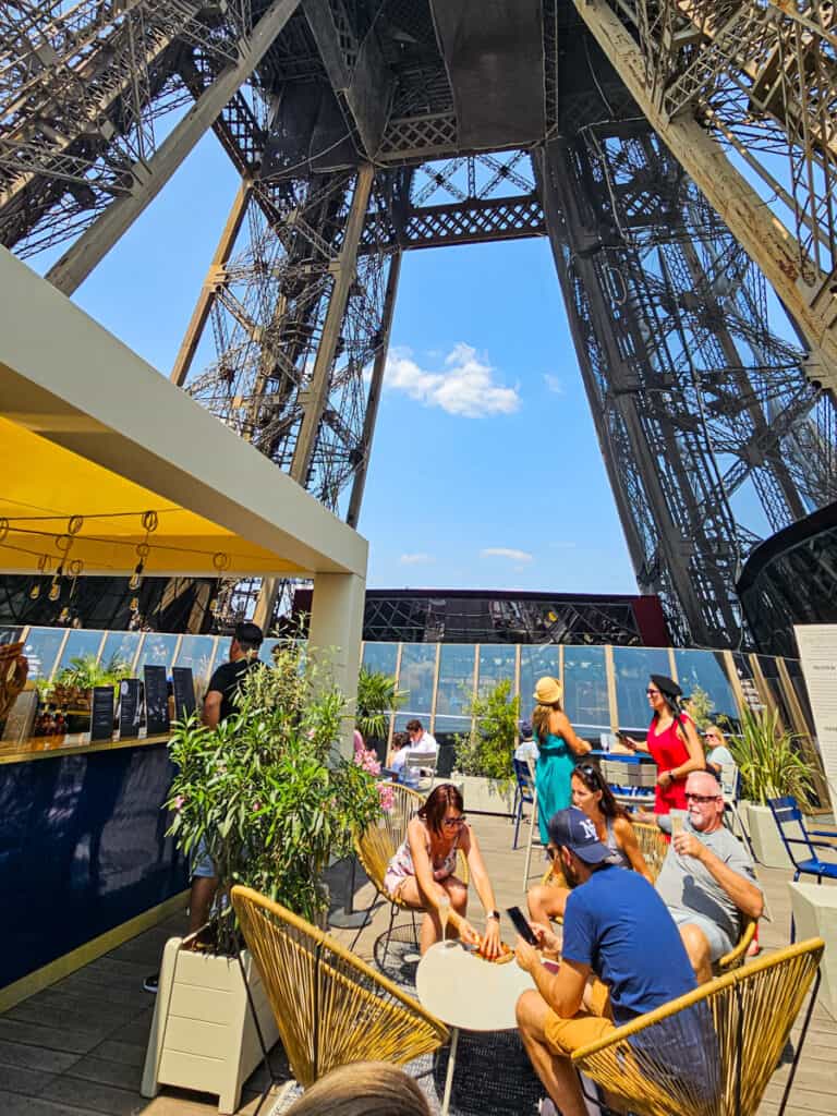 people sitting at cafe seats under eiffel tower on first floor