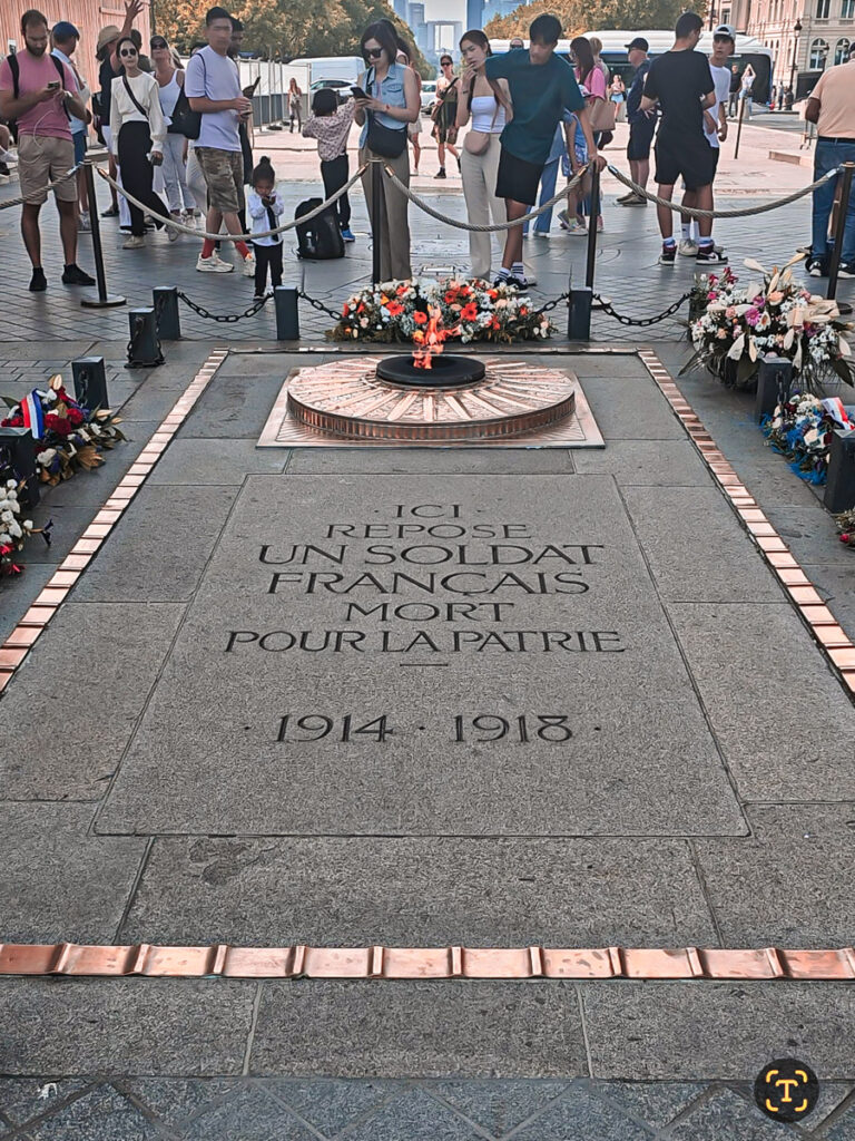 people looking at the eternal flame at the bottom of the arch of triumph paris