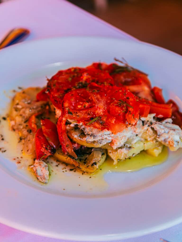 plate with anchovies layered with potato and tomato