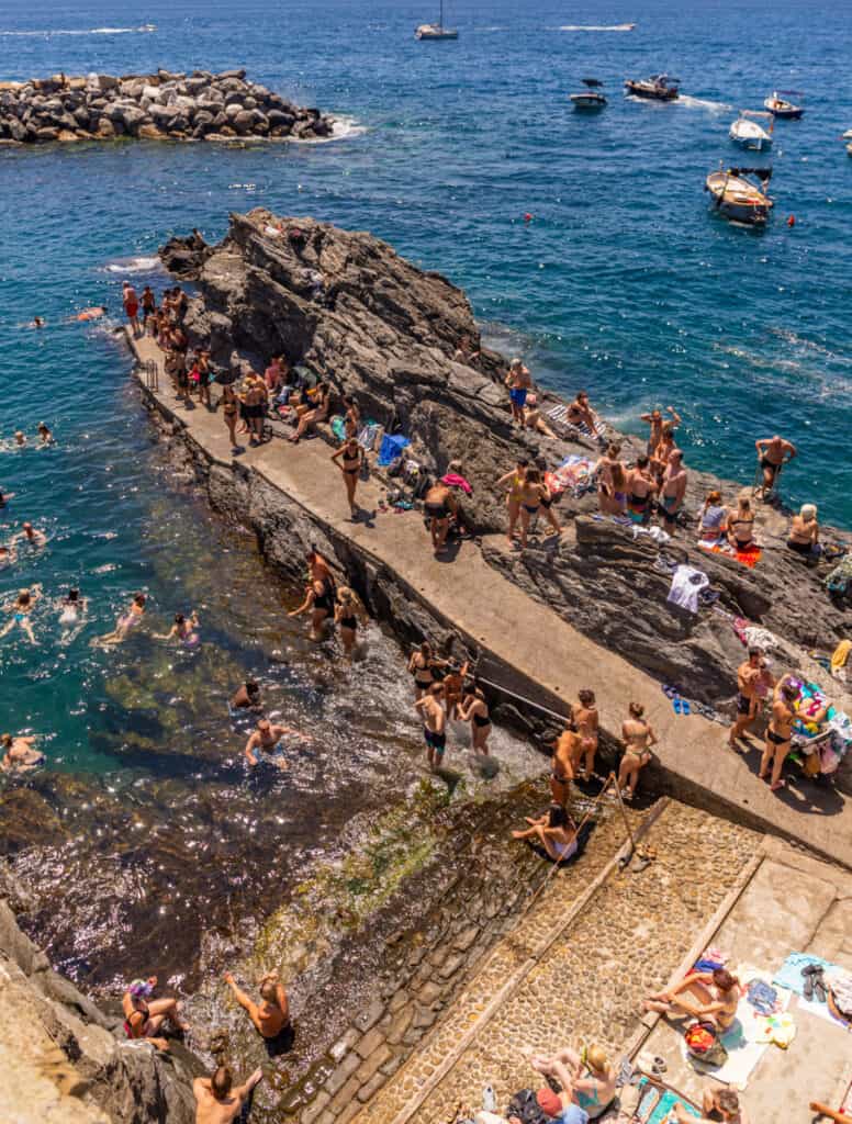 people on rocks jumping off into water