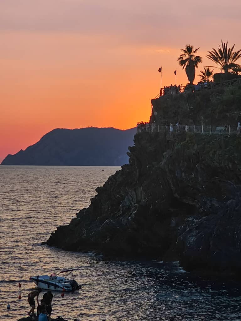 pink sky behind coastline of manarola