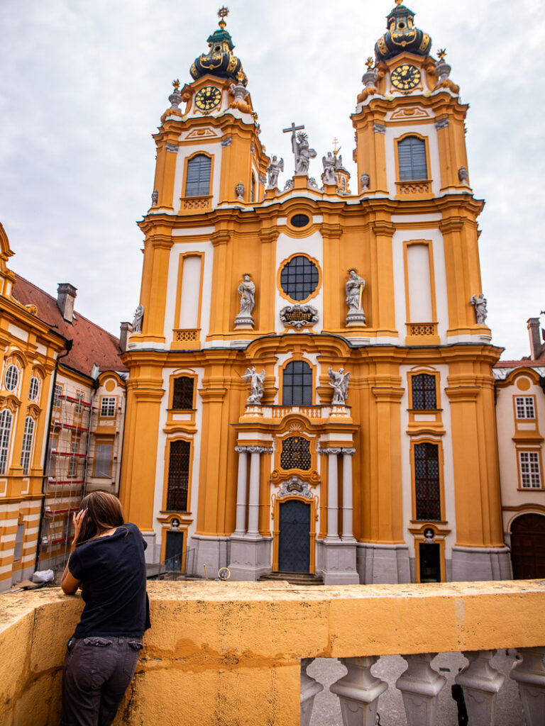 Girl leaning against a wall looking at an Abbey