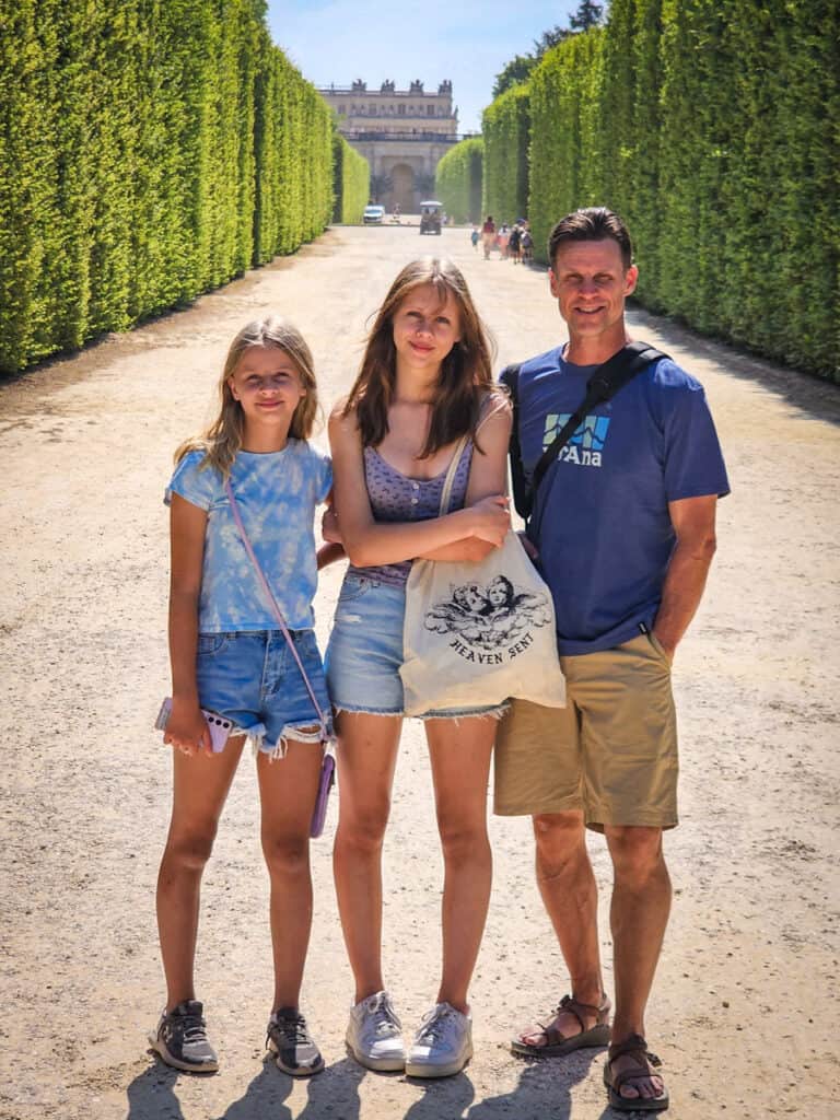 craig and the girls on a dirt path in between two rows of hedges