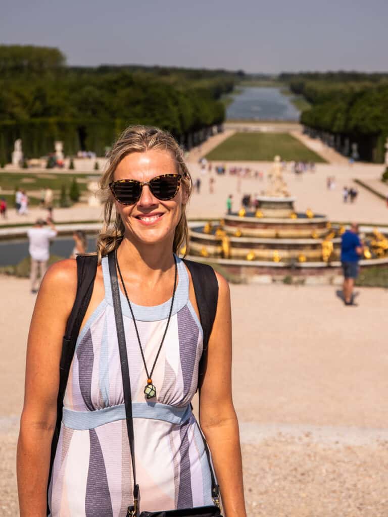 caz posing at camera with grand canal of versaille behind her