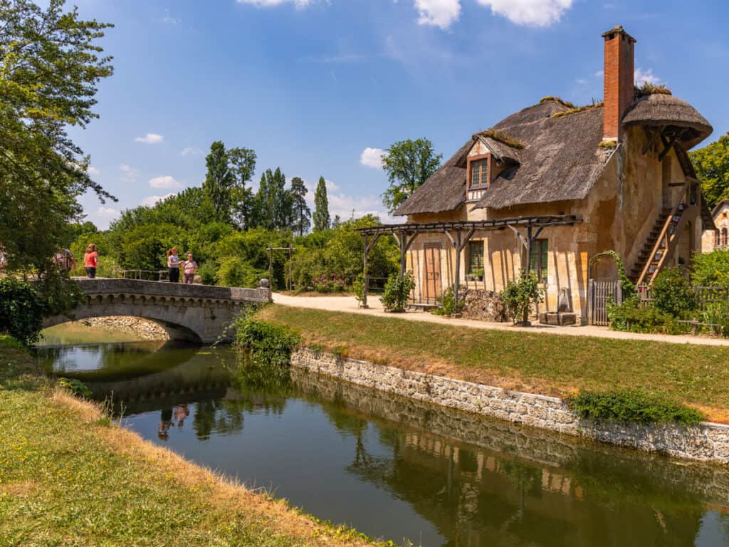 canal with bridge going over it in front of farmhouse