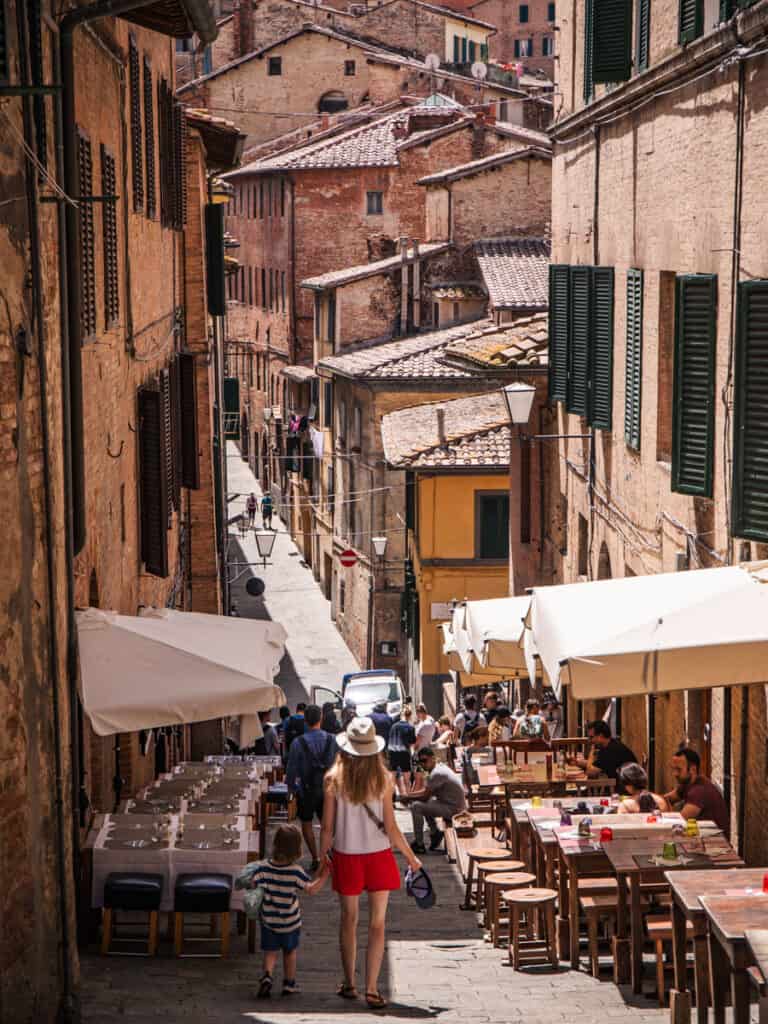 woman walking down narrow street lined with medieval shop fronts