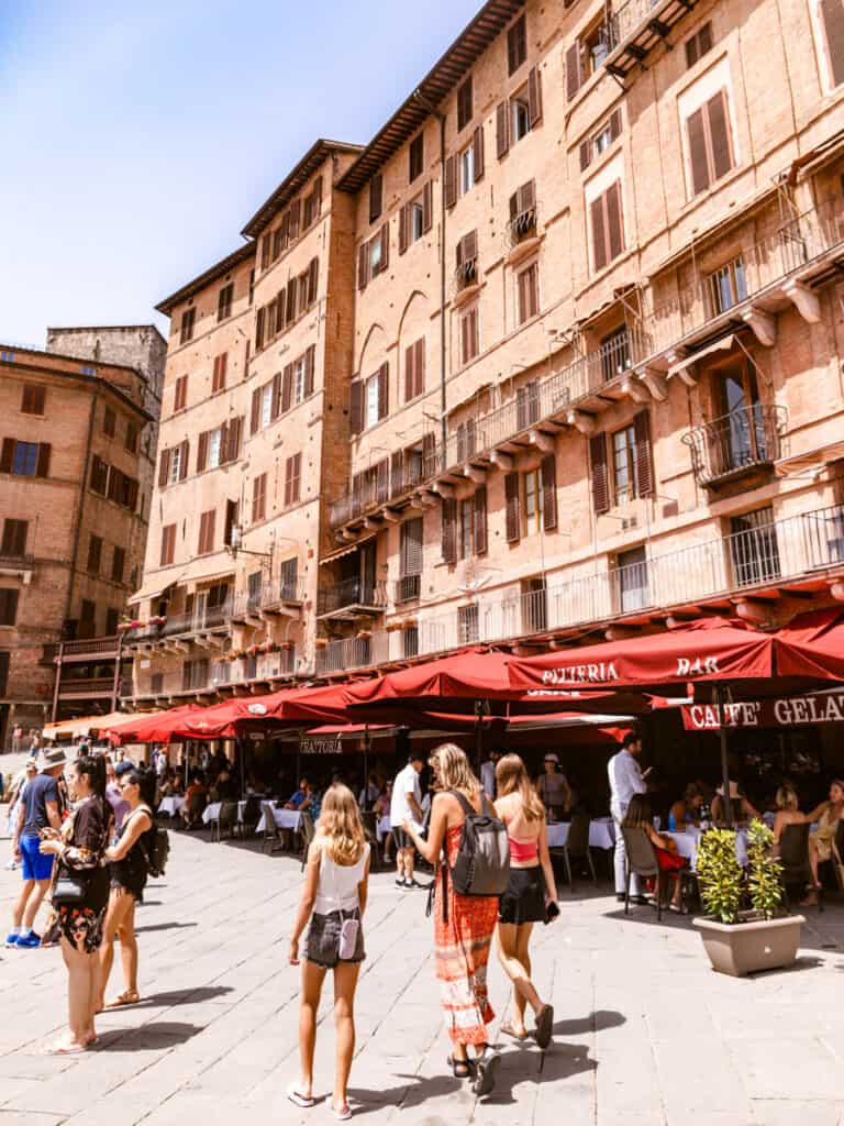 caz and girls walking past restaurants on Piazza del Campo