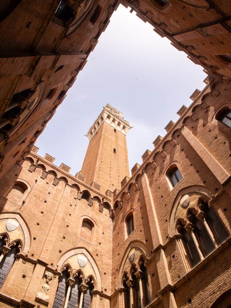 view of Torre del Mangia through hole in courtyard