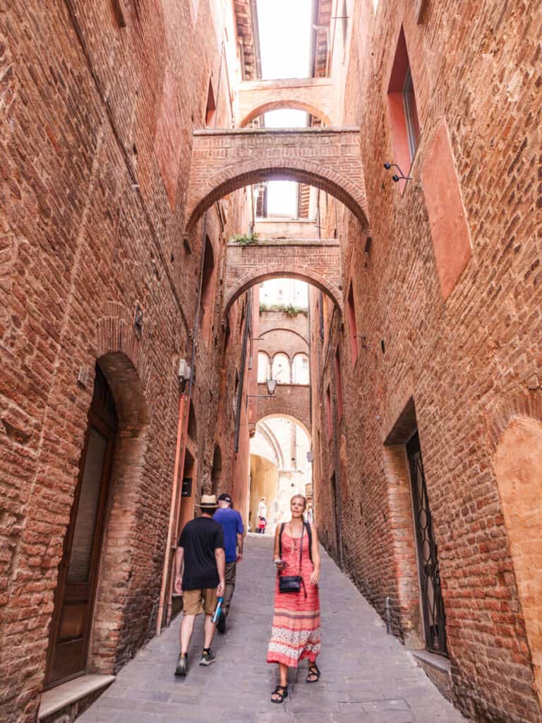 caroline walking down narrow street with high walls