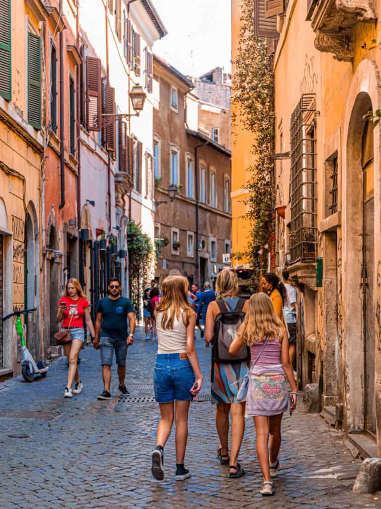 caz and the girls walking down rome street with colorful buildings