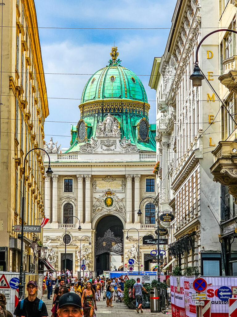 People walking down street with a cathedral in the background.