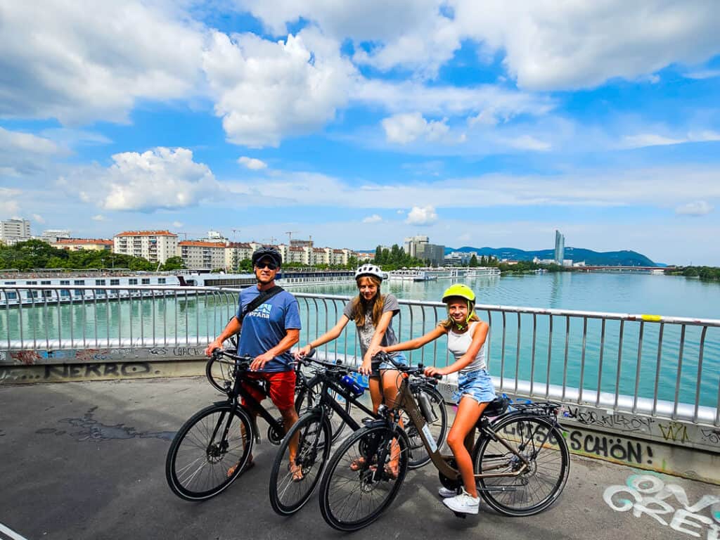 Dad and two daughters biking on a bridge over a river