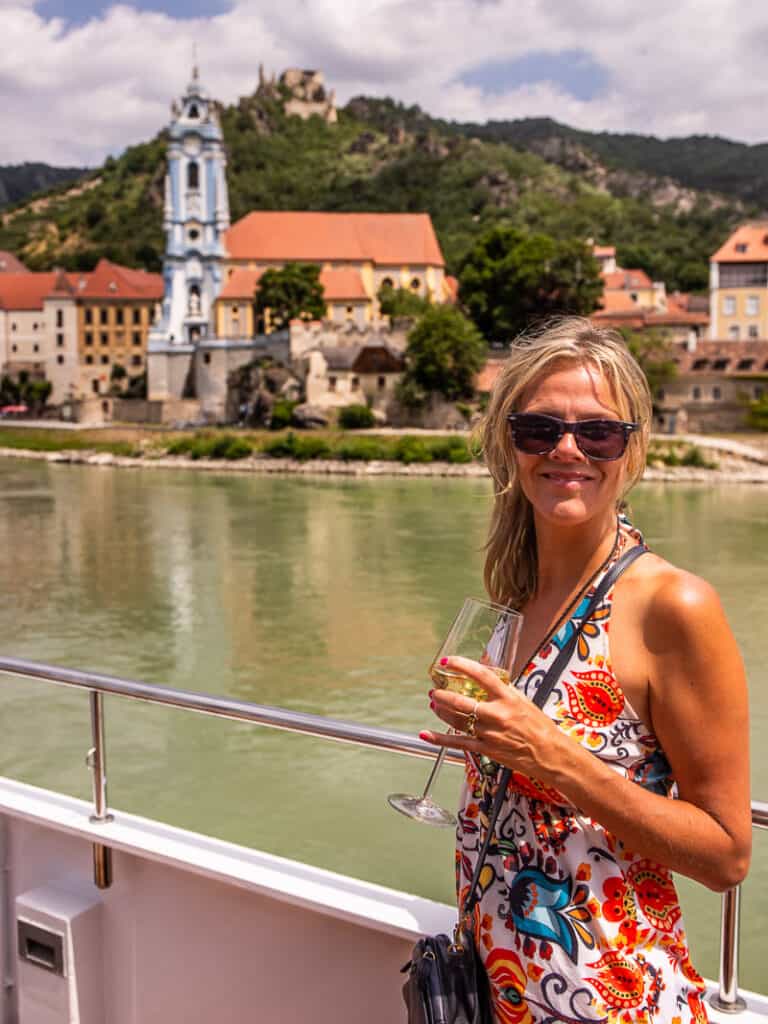 Lady holding a glass or wine on a cruise ship with view of the city