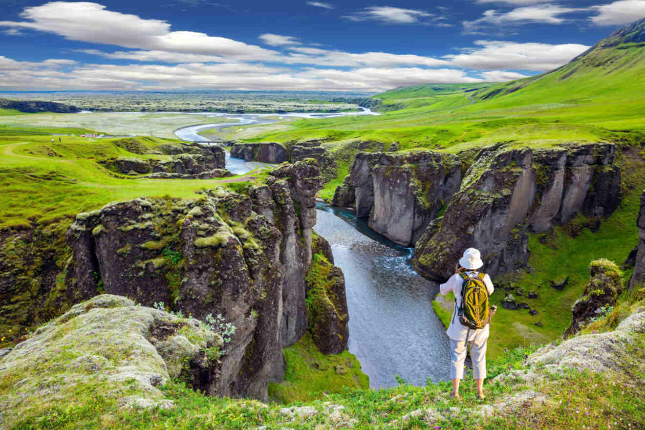 a person standing on top of a cliff overlooking a river in the mountains