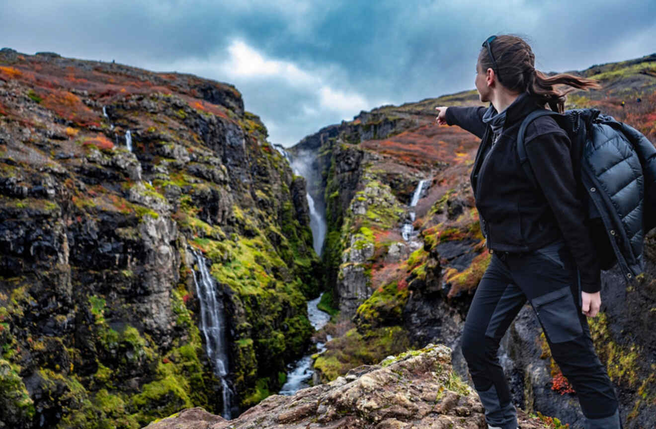 a girl pointing towards waterfalls in a mountain