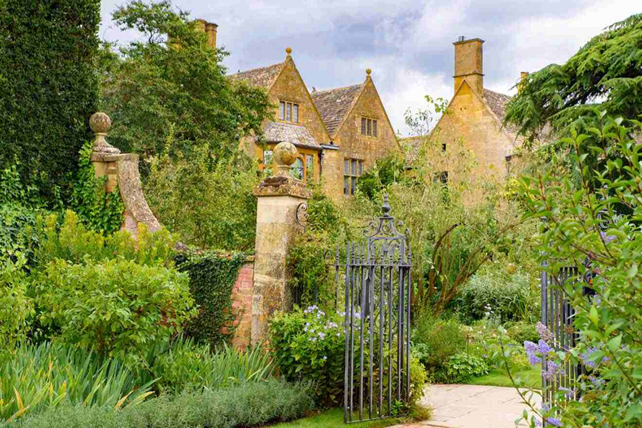 A garden with a gate leading to a house.