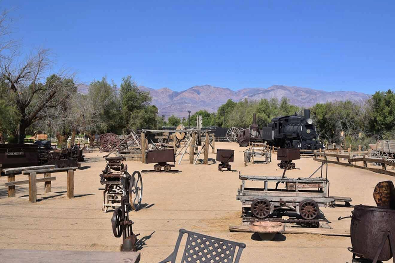 A group of old train tracks in a dirt field with mountains in the background.