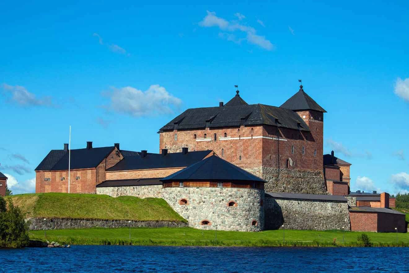 A castle sits on top of a hill next to a body of water.