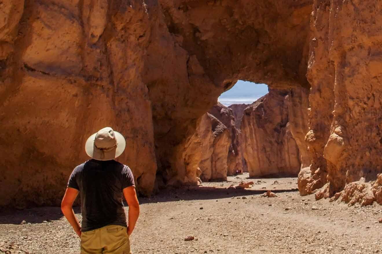 A man standing in front of an arch in a desert.