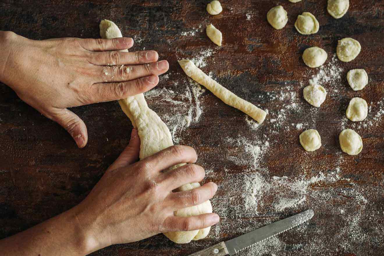 A person kneading dough on a wooden table.