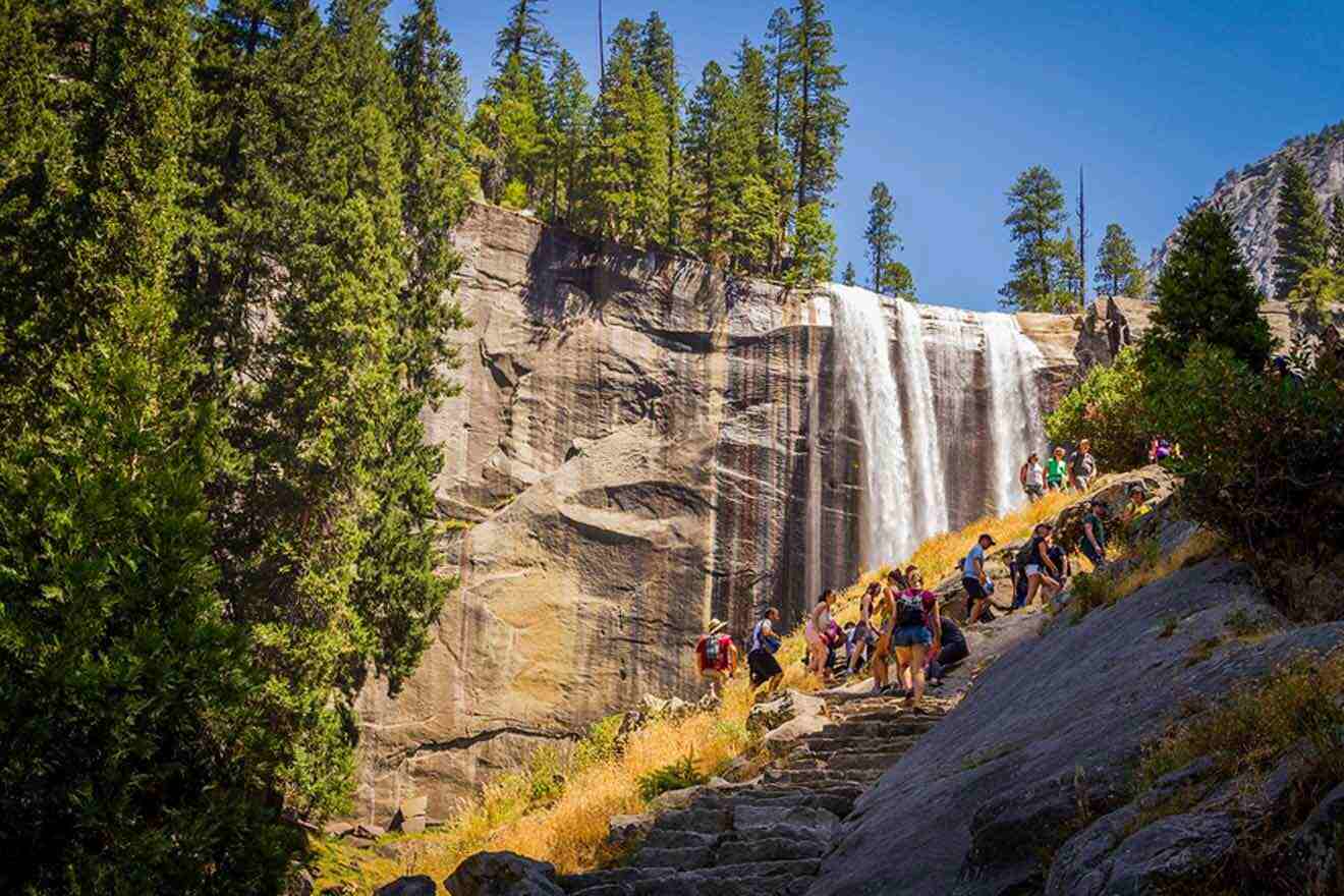 hikers climbing up the starts next to a waterfall