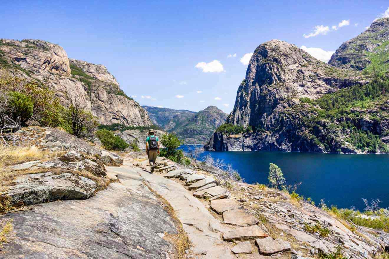 A hiker on a trail near a lake in yosemite national park.