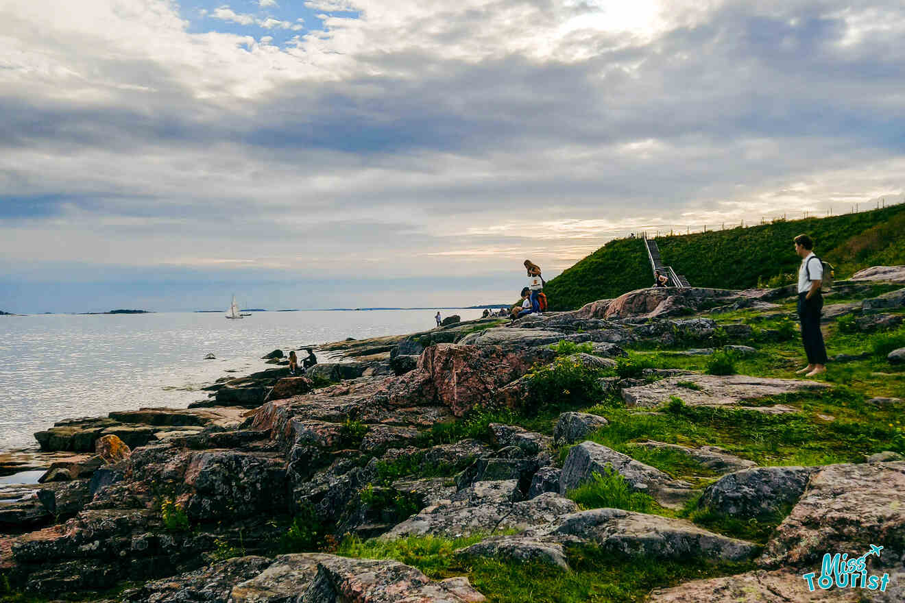 A group of people standing on a rocky cliff overlooking the ocean.