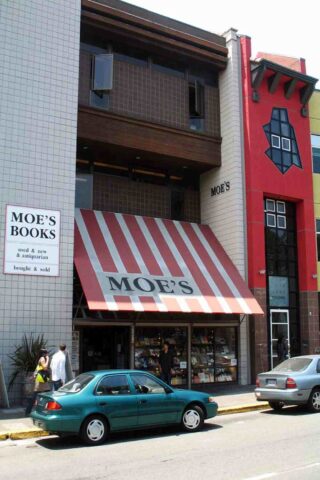 A building with red and white striped awning and parked cars in front of it