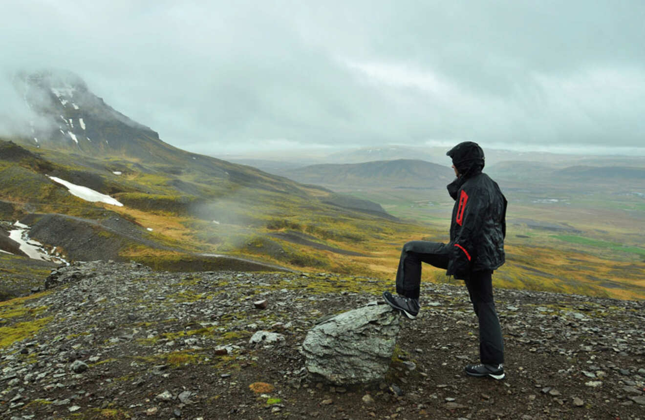 a person leaning on a rock on a mountain overlooking the valley