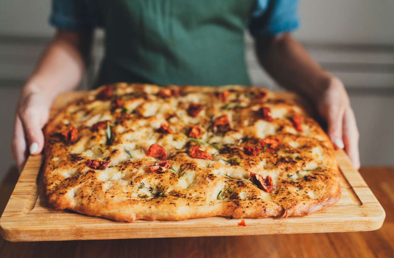 a person holding a tray with focaccia