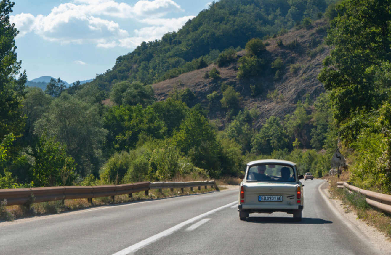 a car driving on a road surrounded by mountains