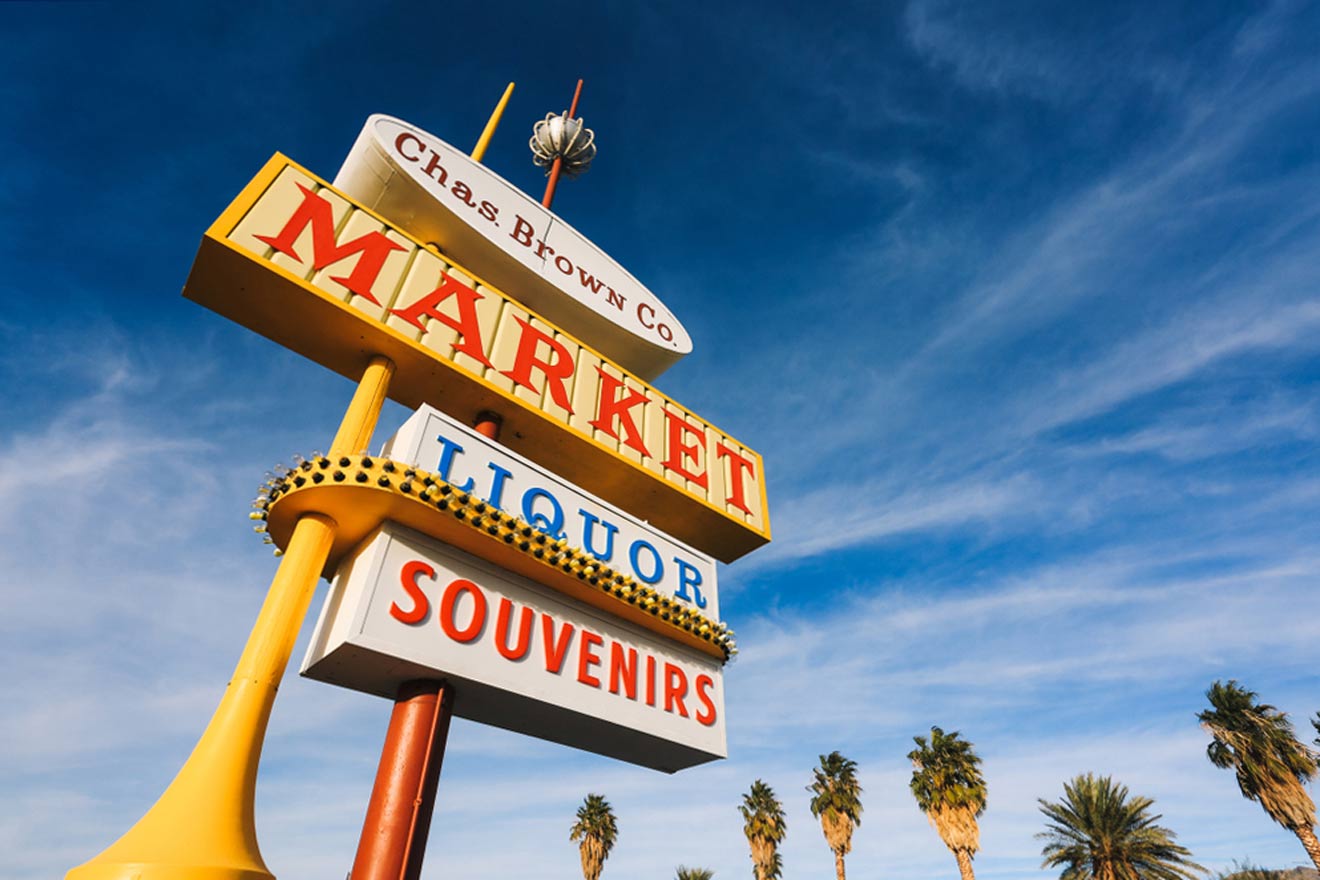 A market sign in front of palm trees.