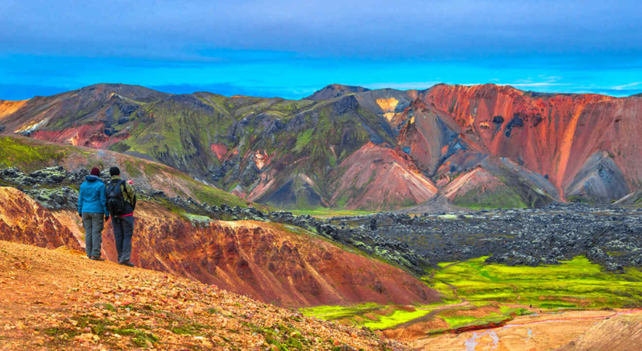 Two people standing on top of a mountain in iceland.