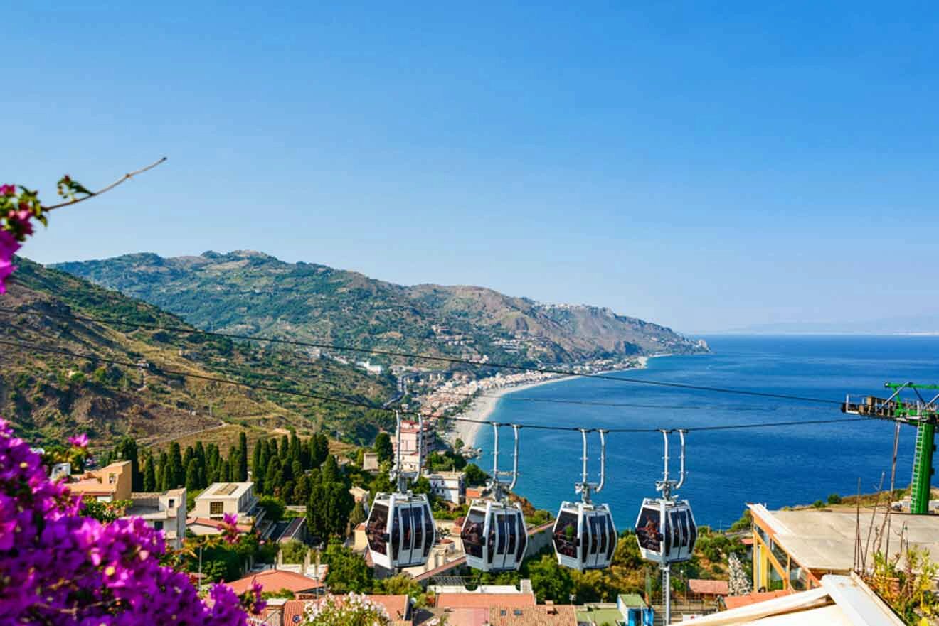 cable cars over a city with the ocean in the background