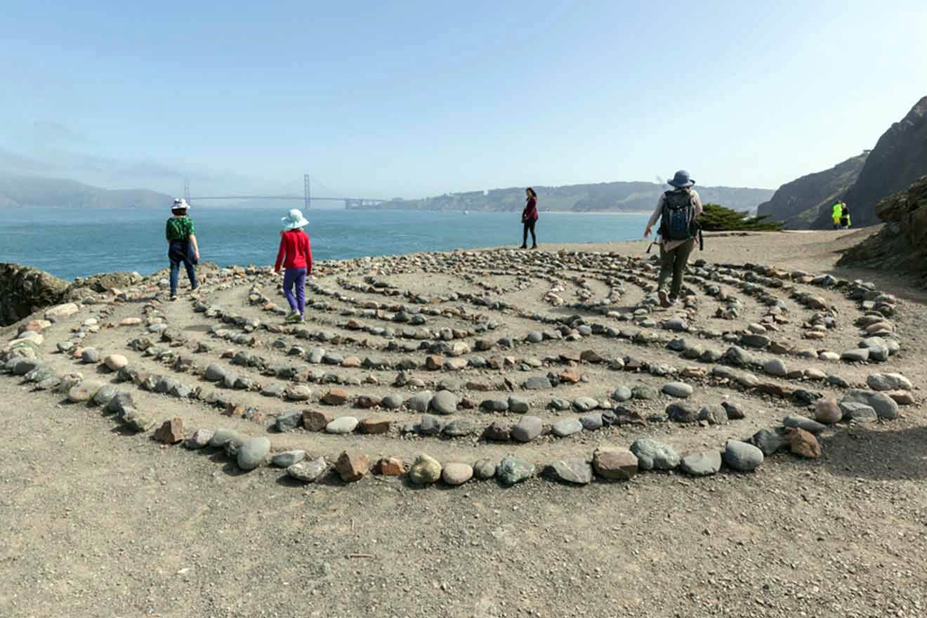 A group of people standing in front of a large stone labyrinth.