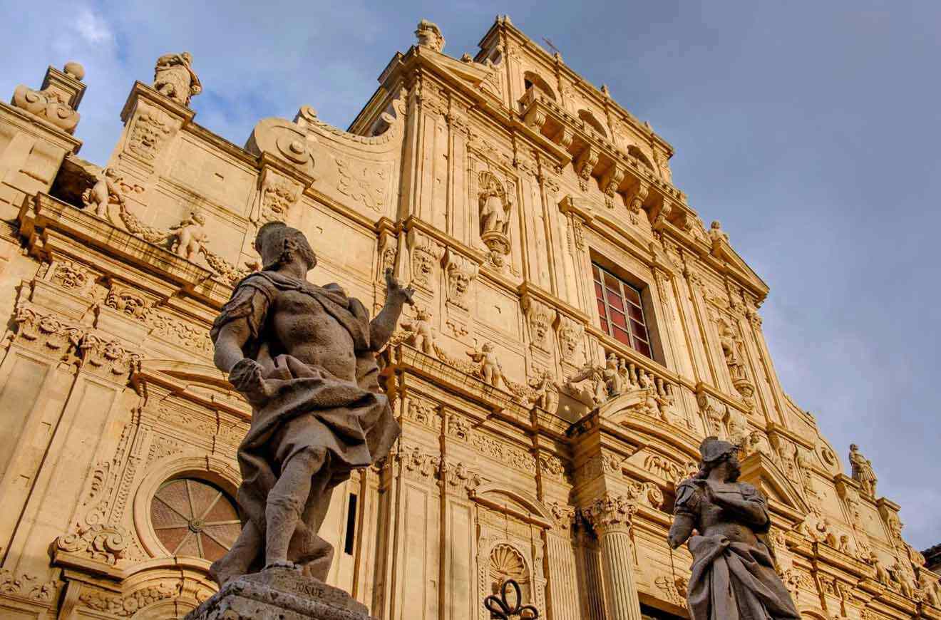 Two statues in front of an ornate building.