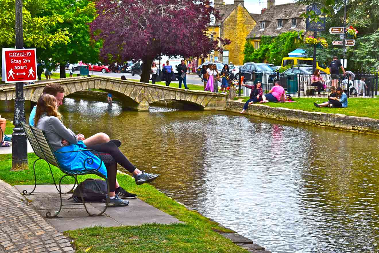 A group of people sitting on a bench near a canal.