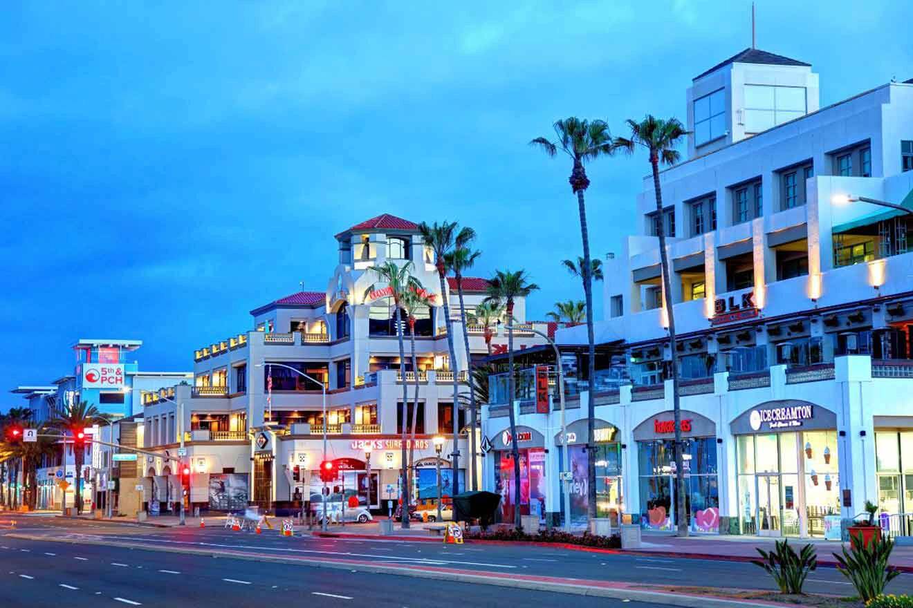 An image of a street with lots of shops and palm trees at sunset