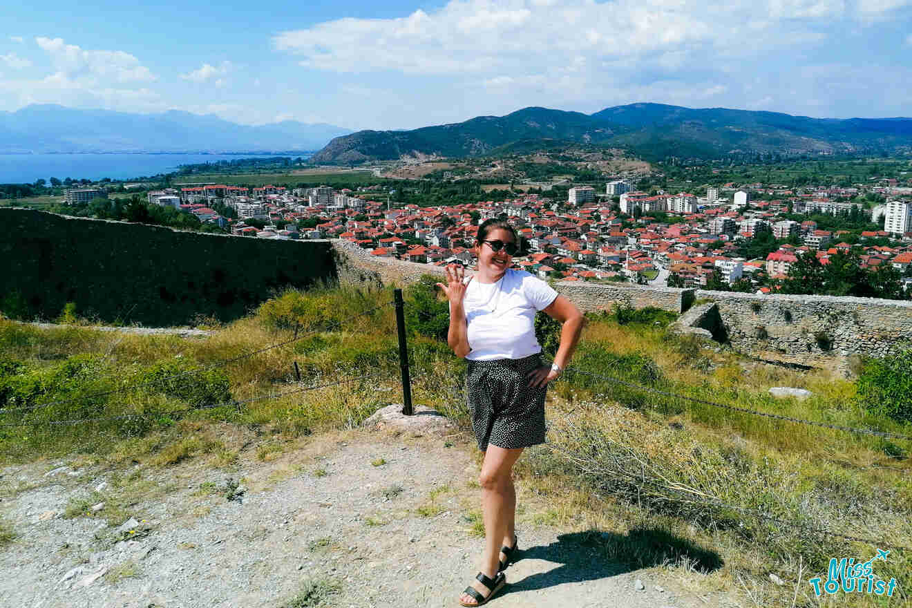 a girl showing off her engagement ring at a fortress with a view of a city in the background