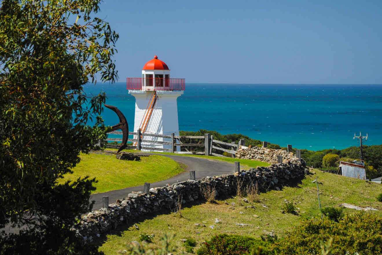 A lighthouse sits on top of a hill overlooking the ocean