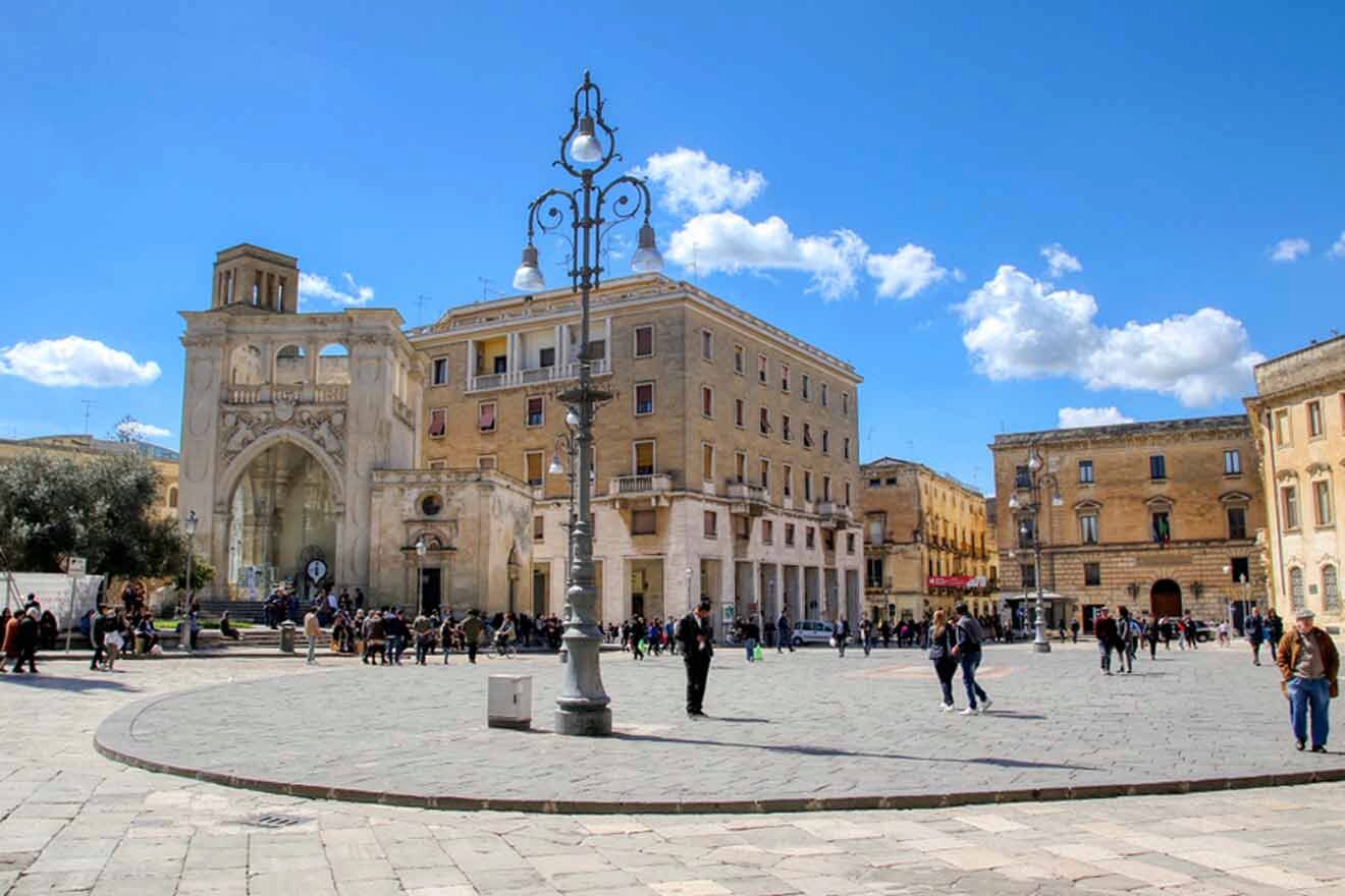 A square with people walking around in front of a building.