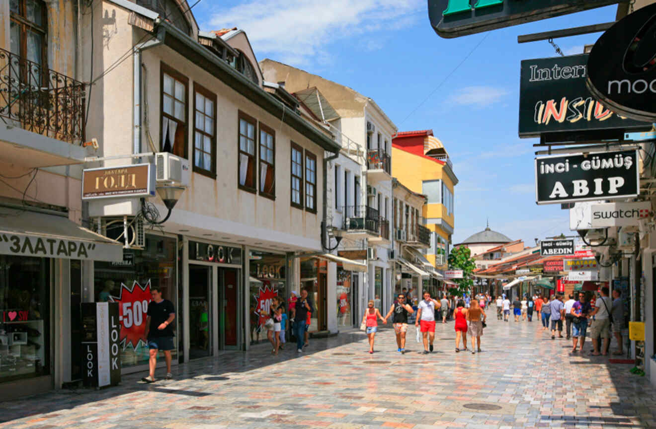 people walking along a wide walking street with shops